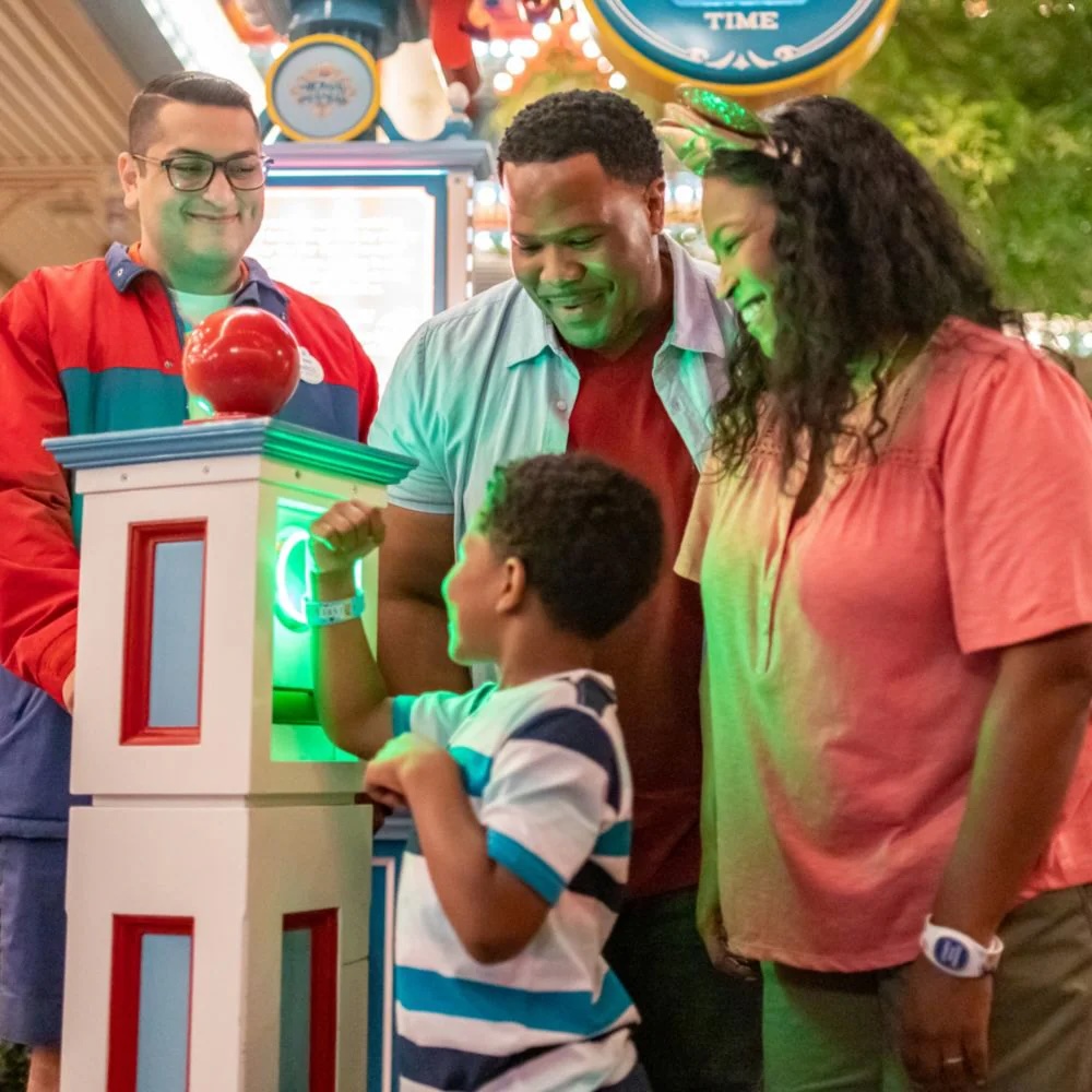 A father, mother, and their son enter a Disney Parks attraction, scanning a Magic Band for their Lightning Lane access.